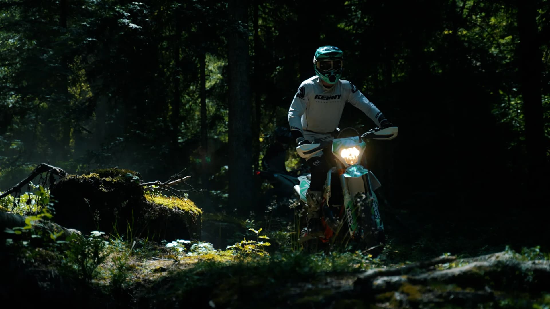 Motard sortant de la forêt, phare allumé